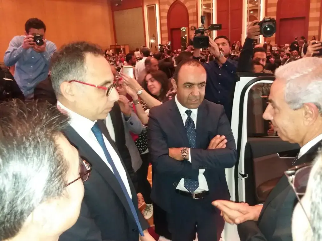 رجال بملابس رسمية يتحدثون خلال الفعالية وسط المصورين