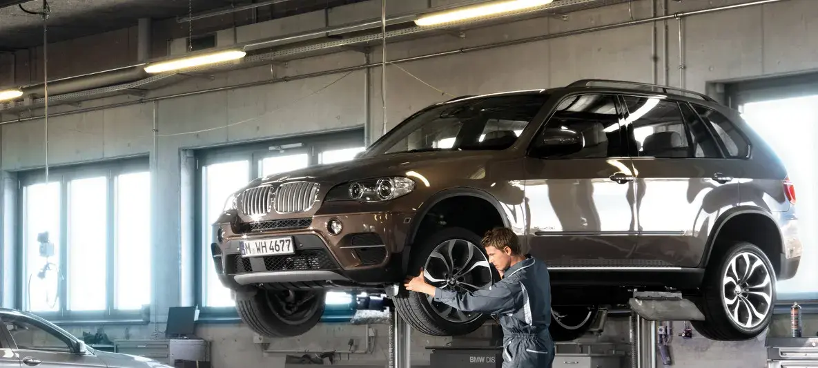 فني يفحص عجلة سيارة BMW مرفوعة داخل مركز صيانة