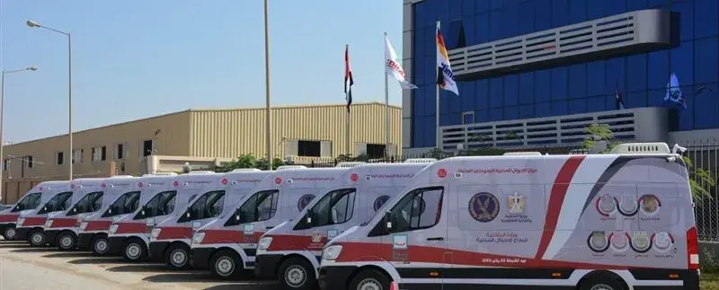 صف من الوحدات المتنقلة البيضاء بخطوط حمراء التابعة لوزارة الداخلية أمام مبنى إداري