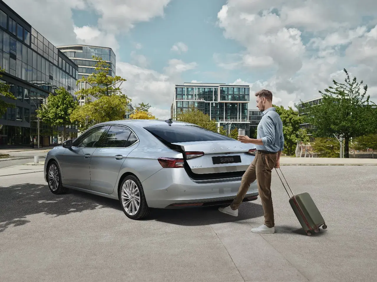 Škoda Superb 2025 فضية من الخلف ورجل يجر حقيبة سفر