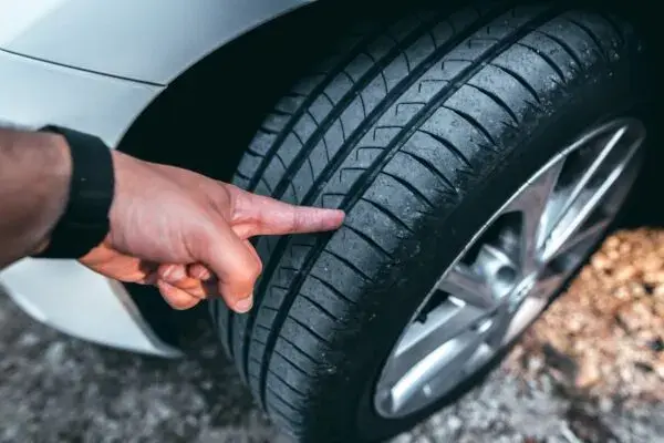 فحص عمق نقشة إطار سيارة بيضاء بالإصبع