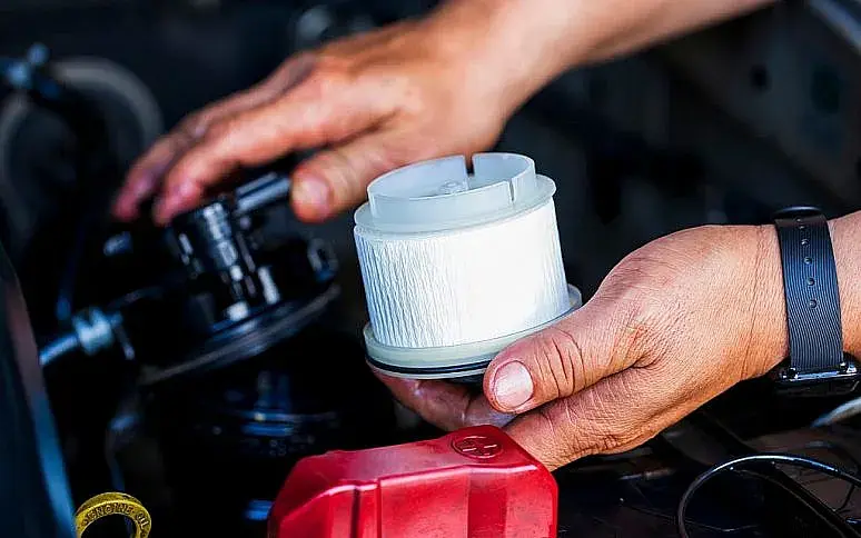 يدان تستبدلان فلتر الوقود داخل حجرة محرك سيارة