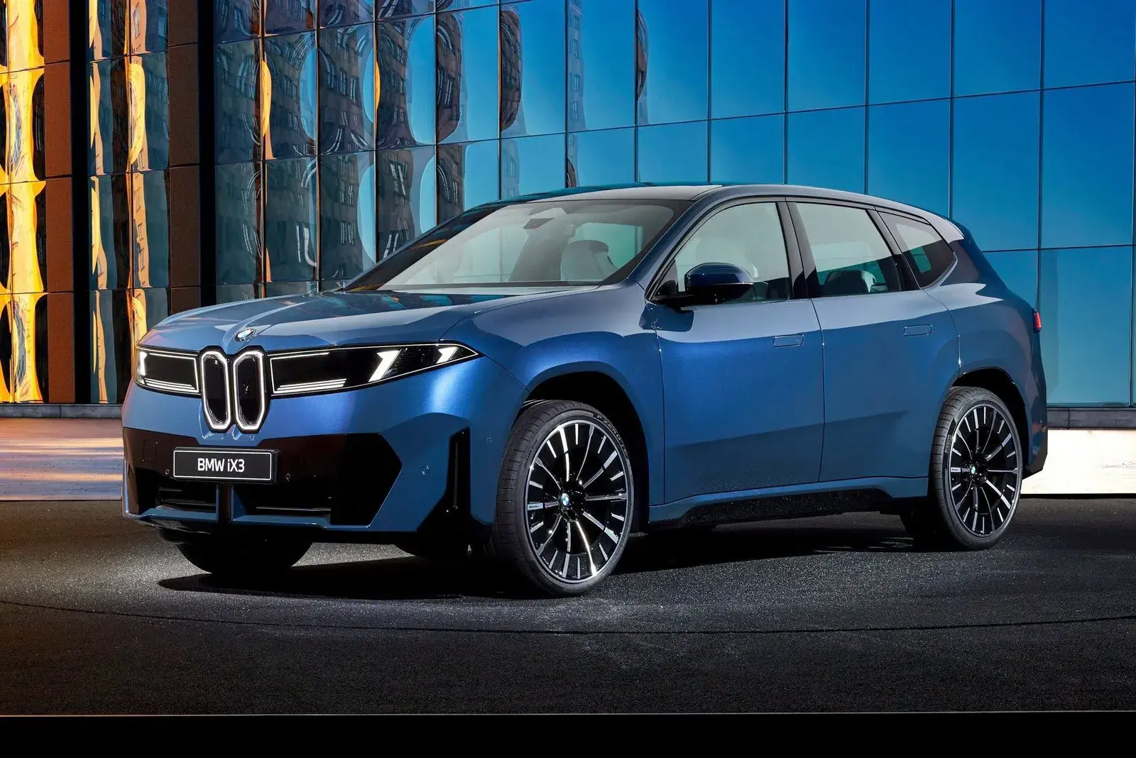 BMW iX3 الجديدة من الزاوية الأمامية أمام مبنى زجاجي