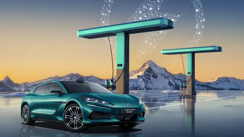 دينزا Z9 GT خضراء من الأمام بجوار محطتي شحن سريع وخلفها جبال مغطاة بالثلوج