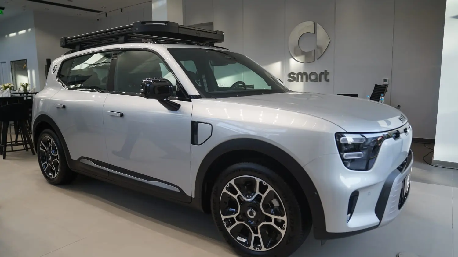 سيارة سمارت SUV فضية بحامل أمتعة على السقف من الأمام الجانبي في صالة عرض
