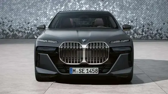 BMW 760i xDrive رمادية داكنة من الأمام بشبكة الكلى الكبيرة وجدار فسيفسائي خلفها