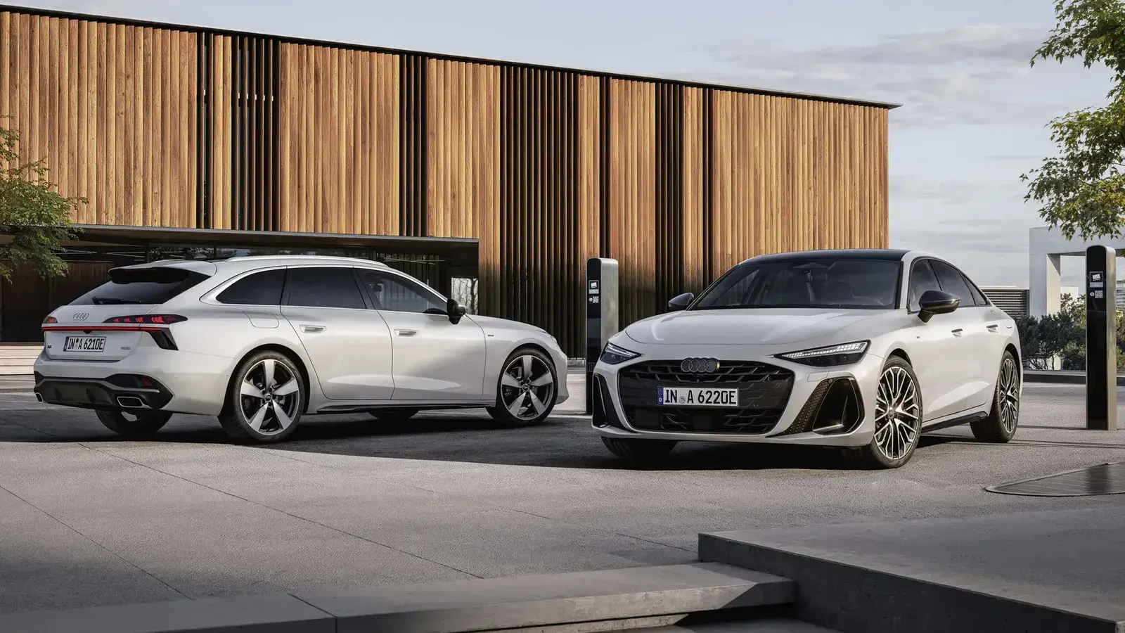 أودي A6 PHEV بنسختي الصالون والاستيت باللون الأبيض أمام مبنى بواجهة خشبية