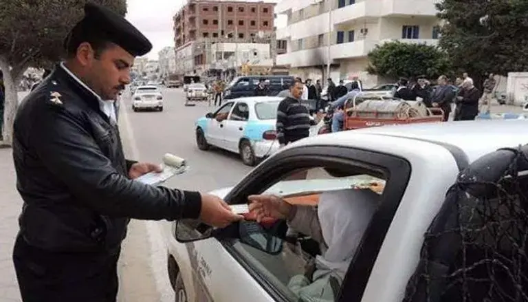 ضابط مرور يتبادل الأوراق مع قائد سيارة بيضاء في الشارع