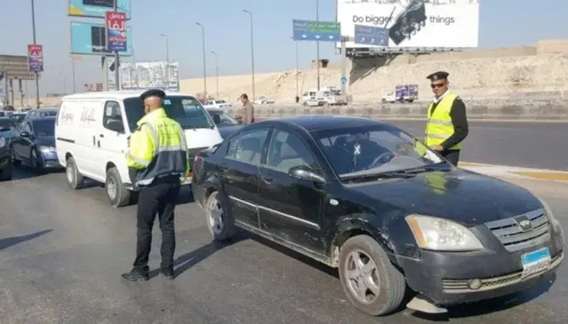 رجلا مرور يستوقفان سيارة سوداء على طريق سريع خلال حملة مرورية