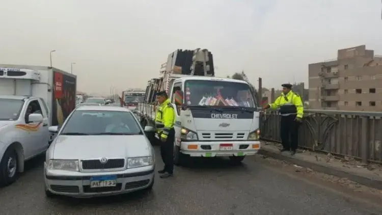 رجال مرور يستوقفون سيارة ملاكي وسيارة نقل خفيف على أحد الطرق