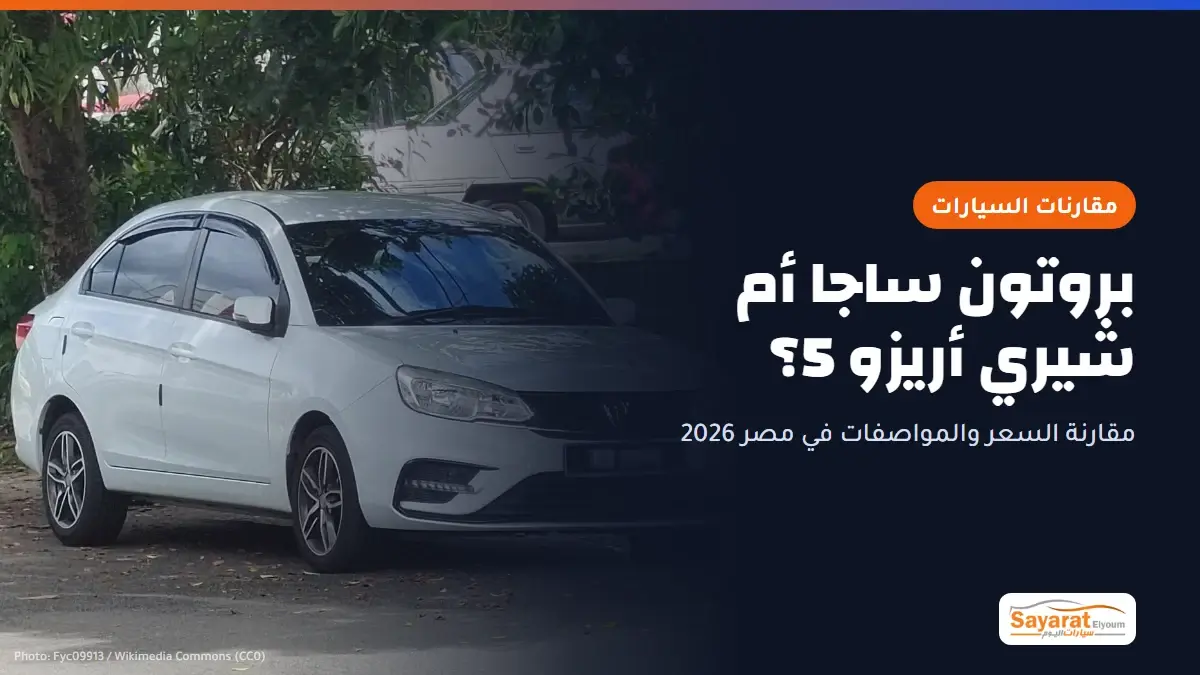 بروتون ساجا أم شيري أريزو 5؟: سيارة بروتون ساجا سيدان بيضاء من الجيل الحالي متوقفة تحت الأشجار، تظهر من الأمام والجانب بشبكها الأسود وشعار بروتون وجنوطها الألومنيوم، ولوحتها مموهة