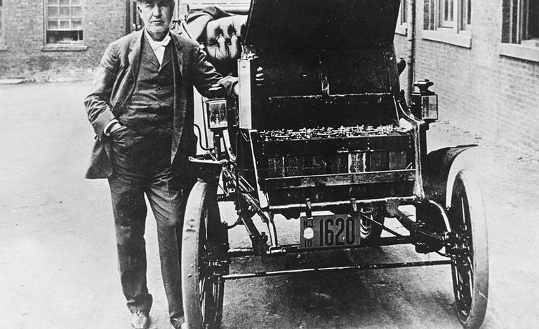 توماس إديسون يقف مع سيارته الكهربائية التي تعمل بالبطارية. السيارة صنعتها شركة Baker Motor Vehicle عام 1895 في كليفلاند.

